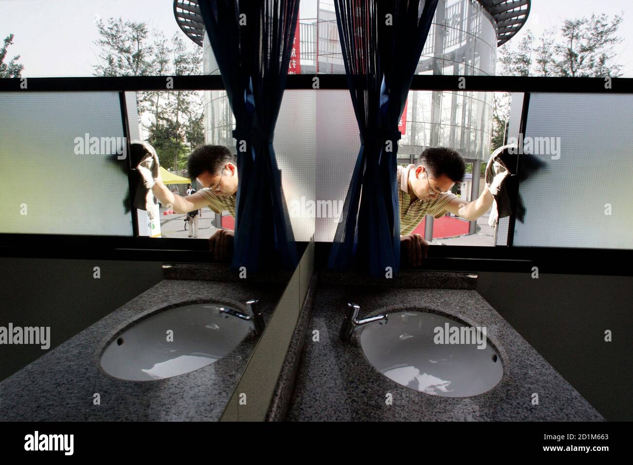 A worker cleans the windows of an ecological and environmental friendly mobile toilet bus, during the Saving Water Toilet Exhibition for the Beijing Olympics in Beijing June 7, 2006.  The exhibition showcased a range of prototype urinals, bowls, and traditional Asian crouching platforms -- all aimed at having a more positive impact on the environment.  REUTERS/Claro Cortes IV   (CHINA) Stock Photo