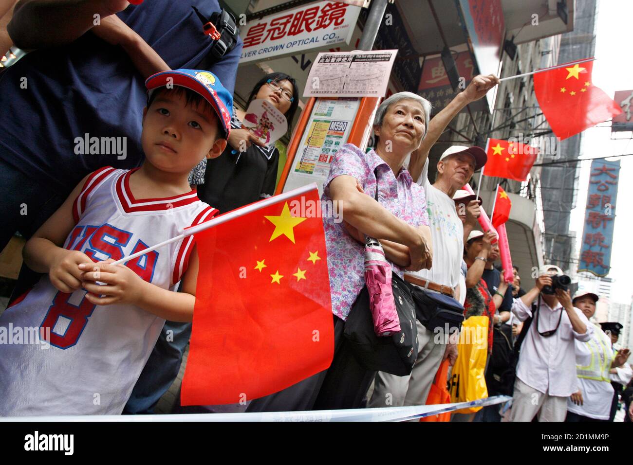 Bystanders hold the Chinese flag as they watch a parade celebrating the