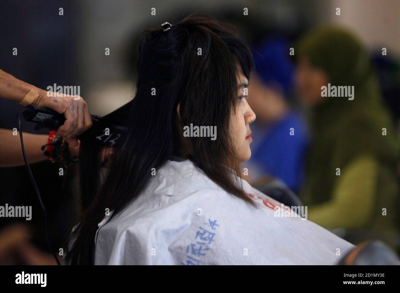 A hair stylist straighten the hair of a customer in a hairdressing salon in  Surabaya, East Java province January 21, 2010. Women's hair styles have  become a hot topic for Indonesia's Muslims