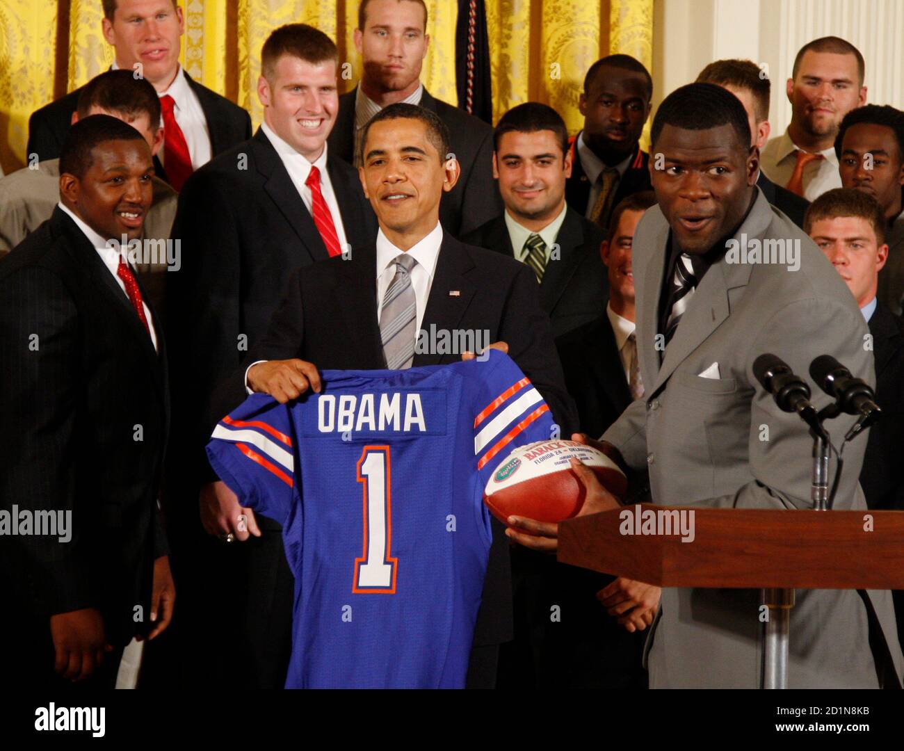 U.S. President Barack Obama (C) is presented with a football jersey by  tight end Cornelius Ingram (R) and other players as Obama welcomes the 2008  NCAA national champions, the University of Florida