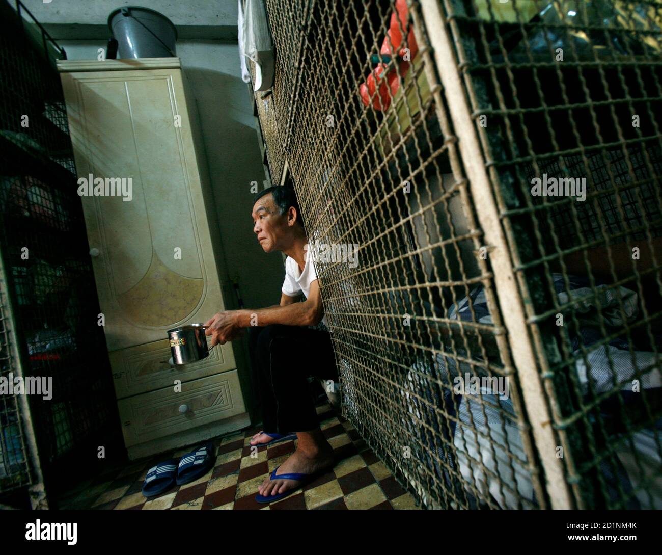 Kong Siu-kau, 63, a cage home resident for several years relying on government pension, sits in his cage bed in Hong Kong March 20, 2009. The monthly rent of a caged-bed, the lowest standard for a shelter in Hong Kong besides sleeping on the street, costs $150. Hong Kong's unemployment rate has risen to five percent, the highest level since June 2006, government said on Tuesday. Labour Secretary Matthew Cheung said the worsening job market was noticeable and he expects unemployment to rise further, government radio reported.   REUTERS/Bobby Yip   (CHINA BUSINESS POLITICS) Stock Photo