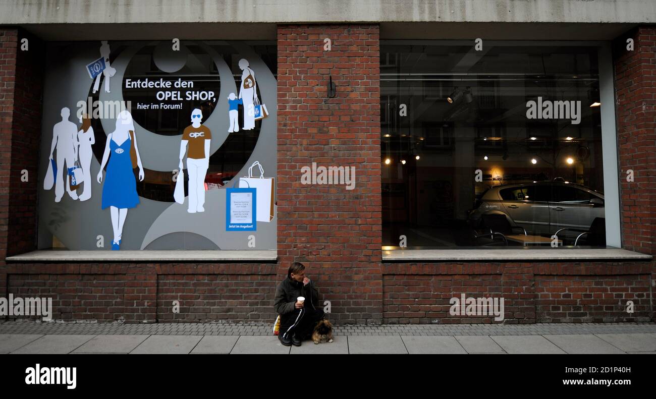 An elderly woman begs for money as she sits outside the showroom and sale  shop of German car manufacturer Opel near the Opel headquarters in  Ruesselsheim, March 9, 2009. German Finance Minister