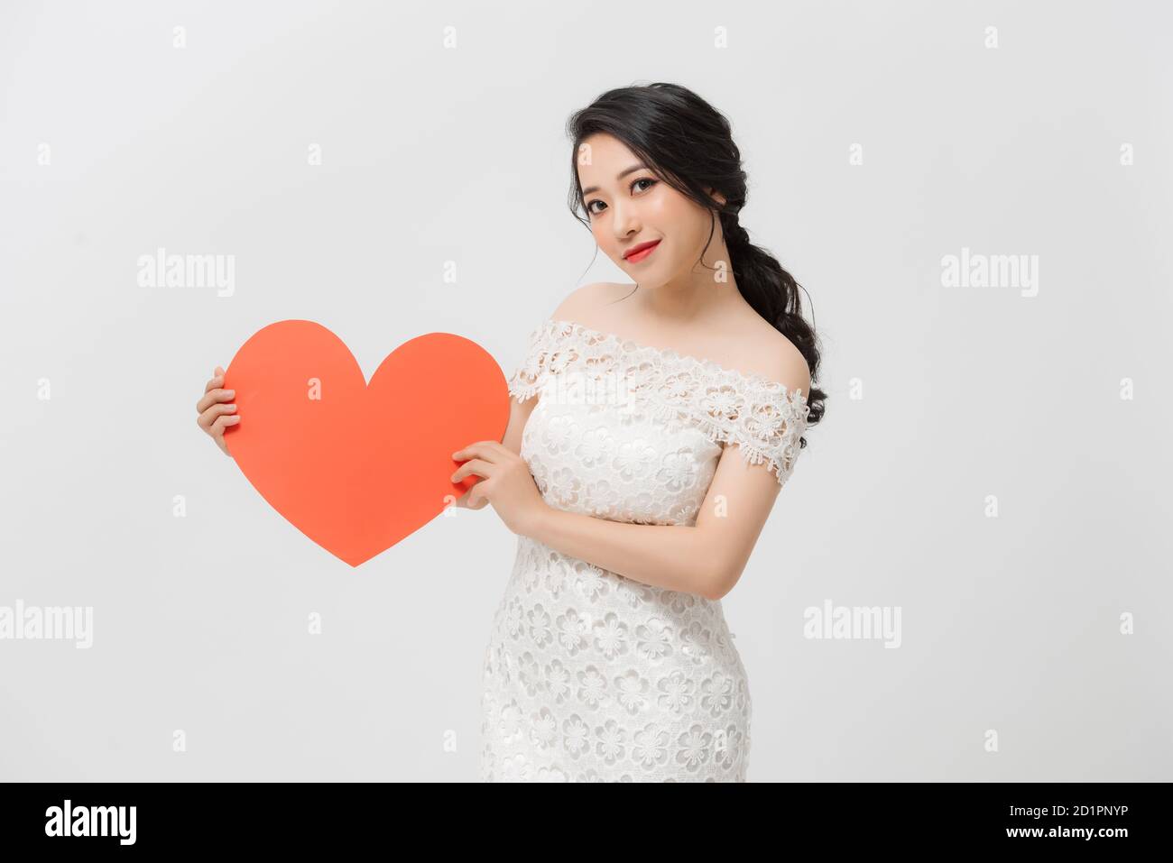 Happy young Asian holding love shape while standing isolated over white ...