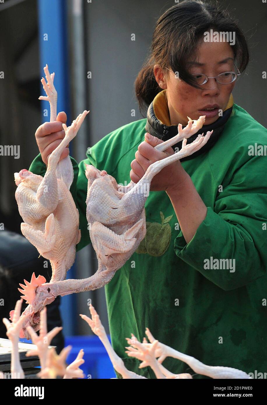 A vendor holds two slaughtered chickens at a poultry market in Hefei, Anhui province March 17, 2008. A top Chinese doctor last week said the H5N1 bird flu virus was mutating, and urged vigilance at a time when seasonal human influenza is at a peak. REUTERS/Jianan Yu (CHINA) Stock Photo
