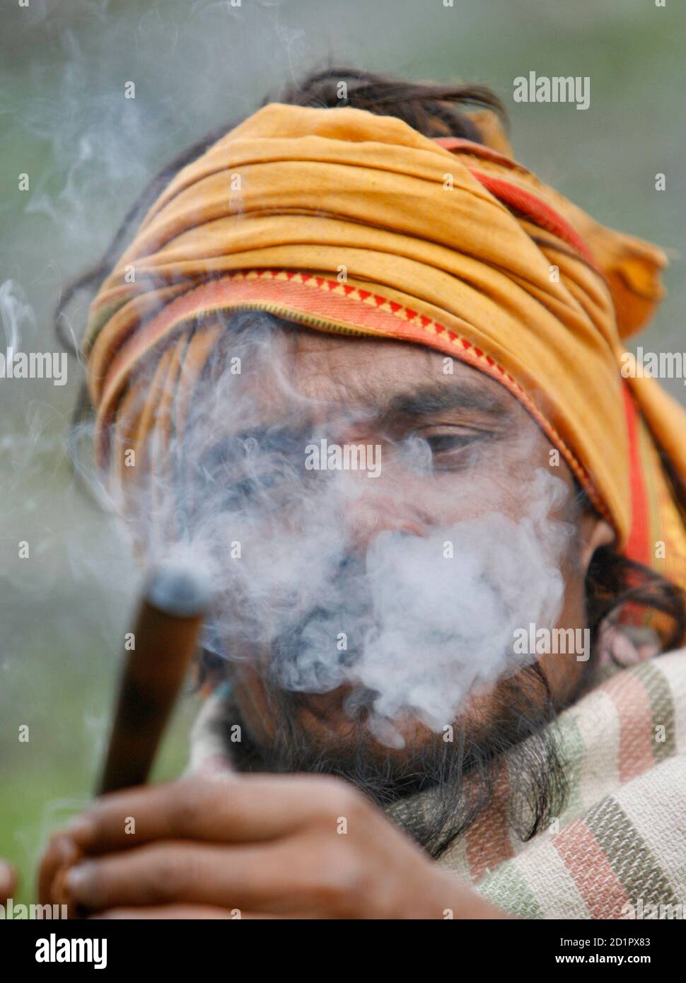 A Sadhu or Hindu holy man smokes a pipe while taking a break from his trek  to the cave of Amarnath, in Pishutop, 114 km (71 miles) southeast of  Srinagar June 22,
