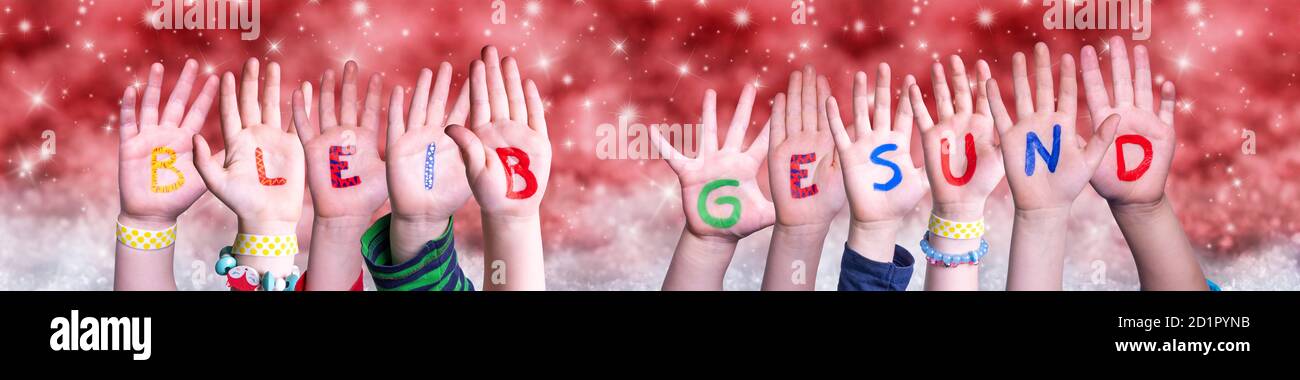 Children Hands Bleib Gesund Means Stay Healthy, Red Christmas Background Stock Photo