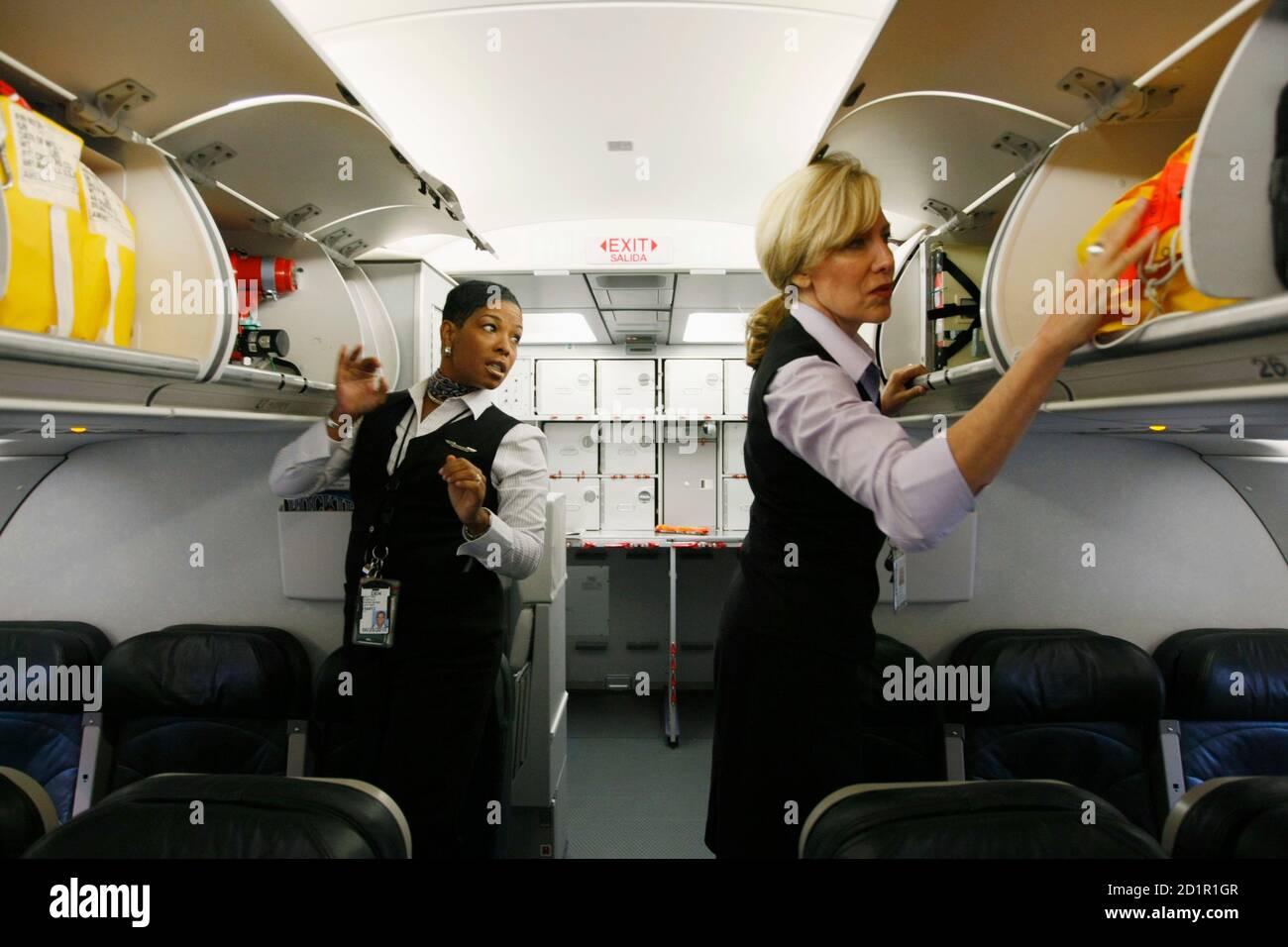 Frontier Airlines flight attendants Arlethia Leopold (L) and Deborah Campos  check safety equipment on their plane prior to a flight to Washington, D.C.  at the Denver airport August 27, 2009. Frontier was