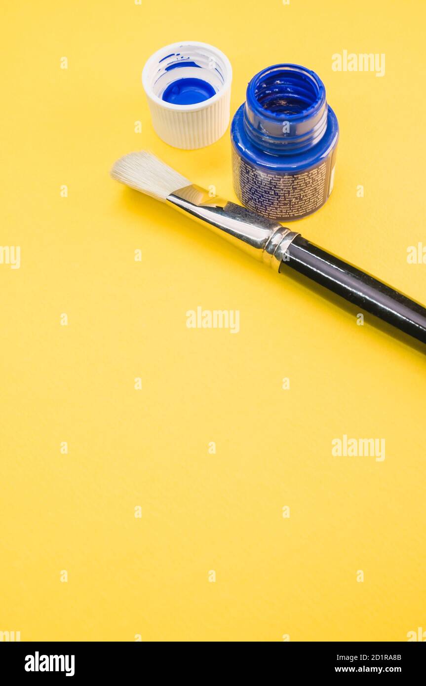 Closeup shot of the acrylic blue paint in the bottle with a paintbrush
