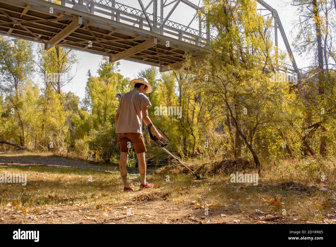 Prospector man uses a metal detector for lost gold treasure from the Walnut Grove Dam in the Hassayampa River outside Kirkland, Arizona in autumn Stock Photo