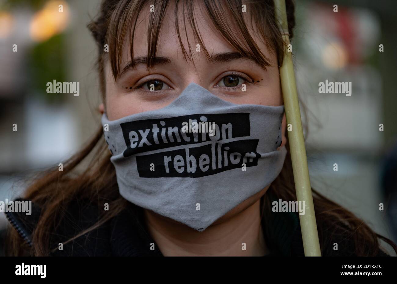 Berlin, Germany. 06th Oct, 2020. An activist of the environmental protection alliance Extinction Rebellion (XR) is standing in front of the Haus der Wirtschaft in the Berlin district of Charlottenburg with a mouth guard with the XR logo, where activists are blocking the street in front of the building. Credit: Paul Zinken/dpa - ATTENTION: Only for editorial use in connection with current reporting and only with full mention of the above credit/dpa/Alamy Live News Stock Photo