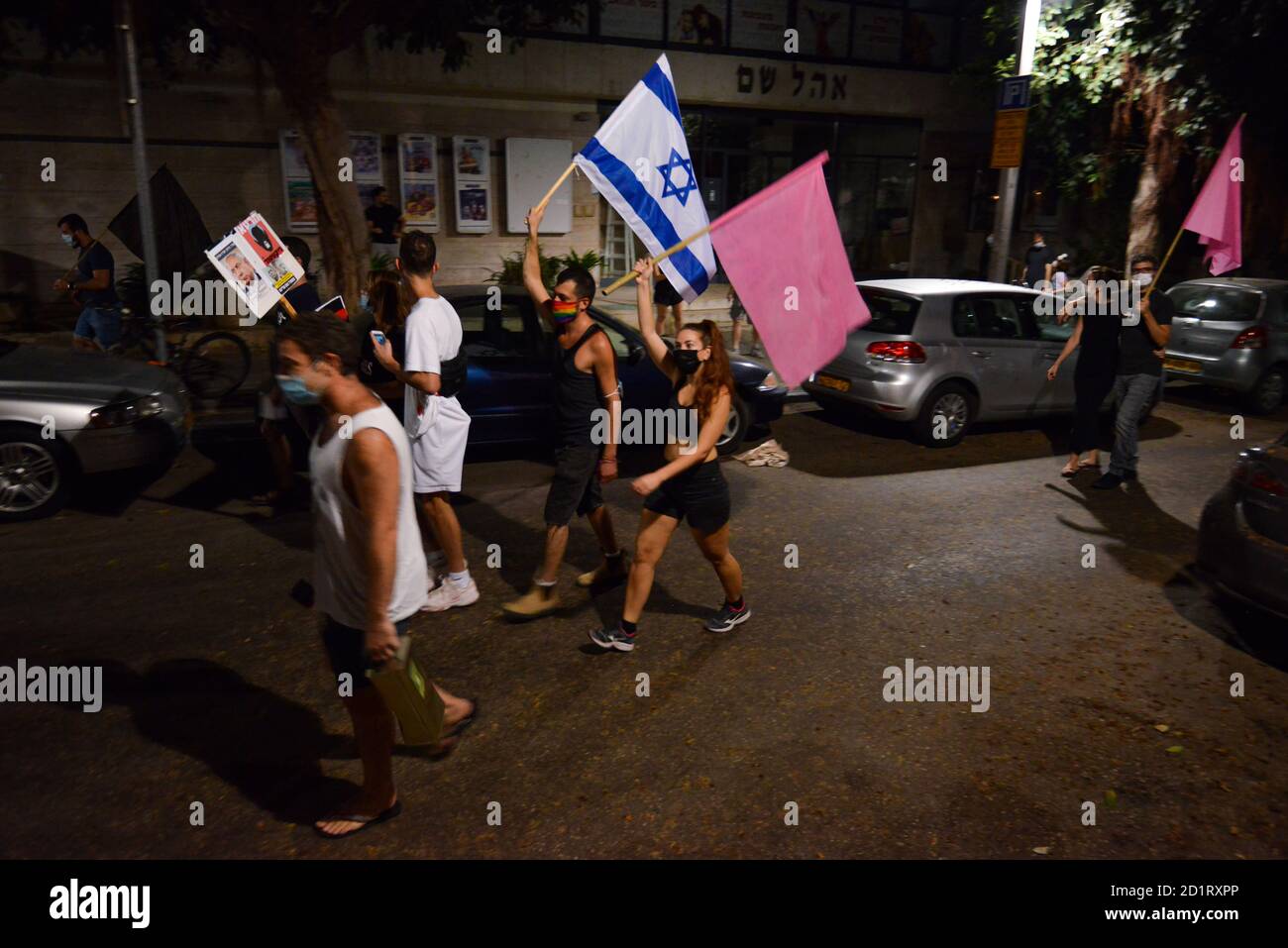 2.10.2020 Tel Aviv, Israel. Protest against Prime minister Netanyahu and second Coronavirus lockdown. Early stages of the protest in which hundreds were marching in Tel Aviv streets calling Bibi Netanyahu to resign. The pink flags symbolize the weakened populations, grace, empathy had become the youth symbol of what they see as the revolution Stock Photo