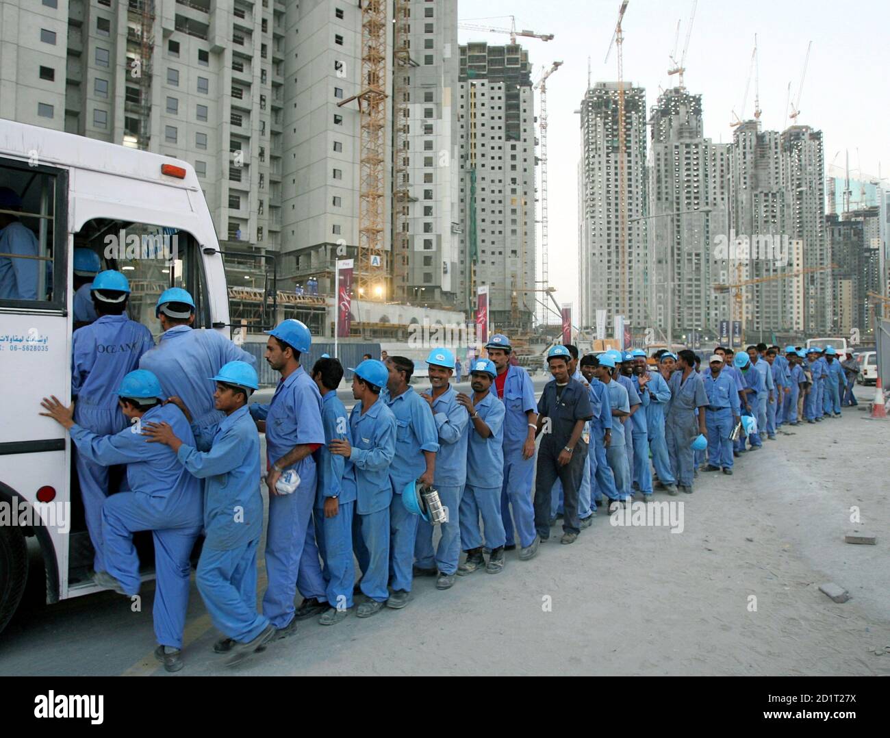 Southasian workers line up to board a bus after a day's work in Dubai on November 18, 2005. Thousands of foreign workers, who are behind the rapid development drive that has transformed the UAE into a modern state, have gone on strike over unpaid wages in the United Arab Emirates this year. The United States has been urging the UAE and other Gulf Arab to conform to the International Labour Organisation's standards. Stock Photo