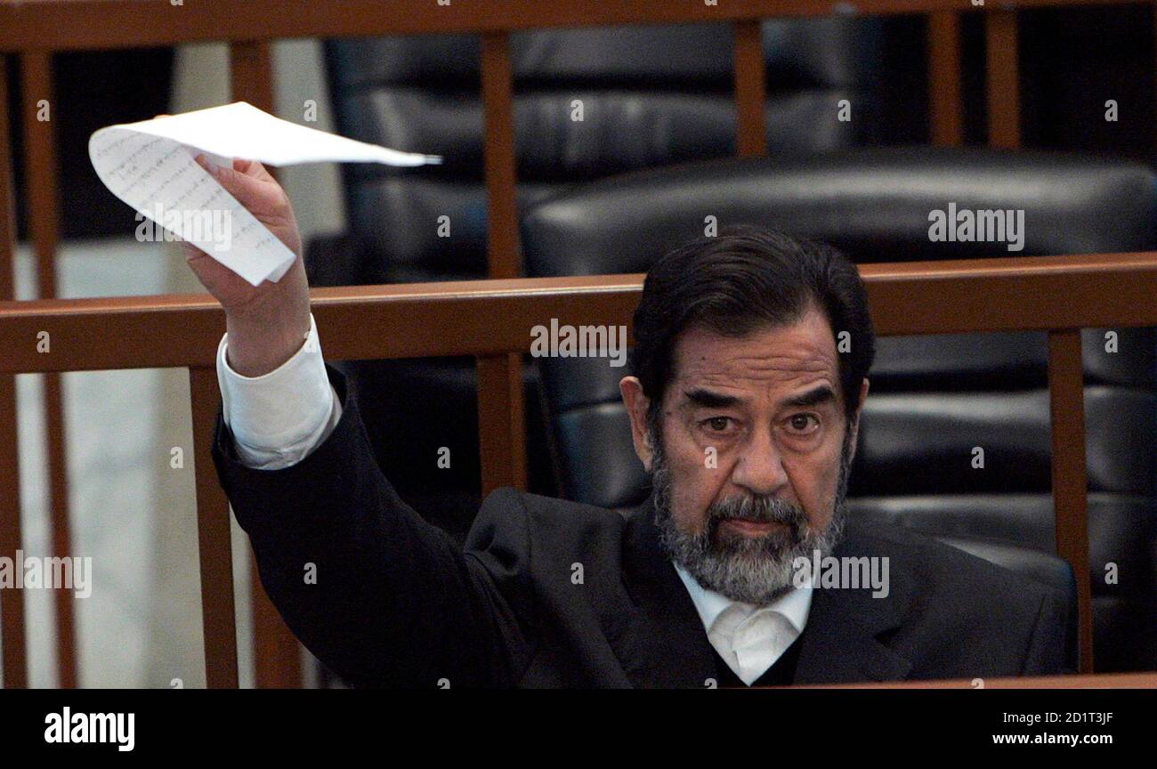Saddam Hussein Holds Up A Piece Of Paper For The Judge During The Continuation Of The Trial In Baghdad December 4 06 Of Saddam And Other Co Defendants In The Anfal Offensive Against