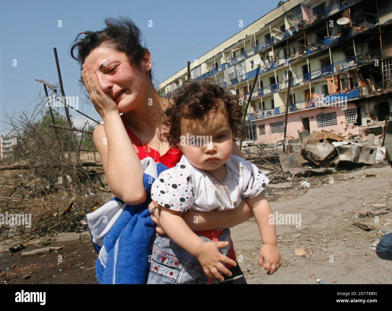 A Georgian woman holding her baby cries at her damaged home in Gori August 10, 2008. Russia has started an operation to storm the Georgian-controlled Kodori gorge in Georgia's breakaway region of