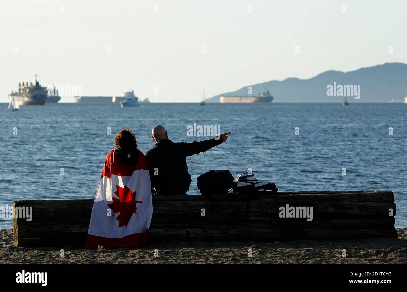 Canadian Olympic fans take a break to enjoy a spring-like day at Vancouver's English Bay during the Vancouver 2010 Winter Olympics February 19, 2010.  REUTERS/Mike Blake (CANADA) Stock Photo