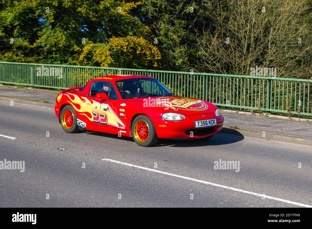 Red 1840cc 1999 90s nineties petrol roadster, red flame decals on customised MAZDA Mx-5 Sports car in motion crossing motorway bridge near Manchester, UK Stock Photo