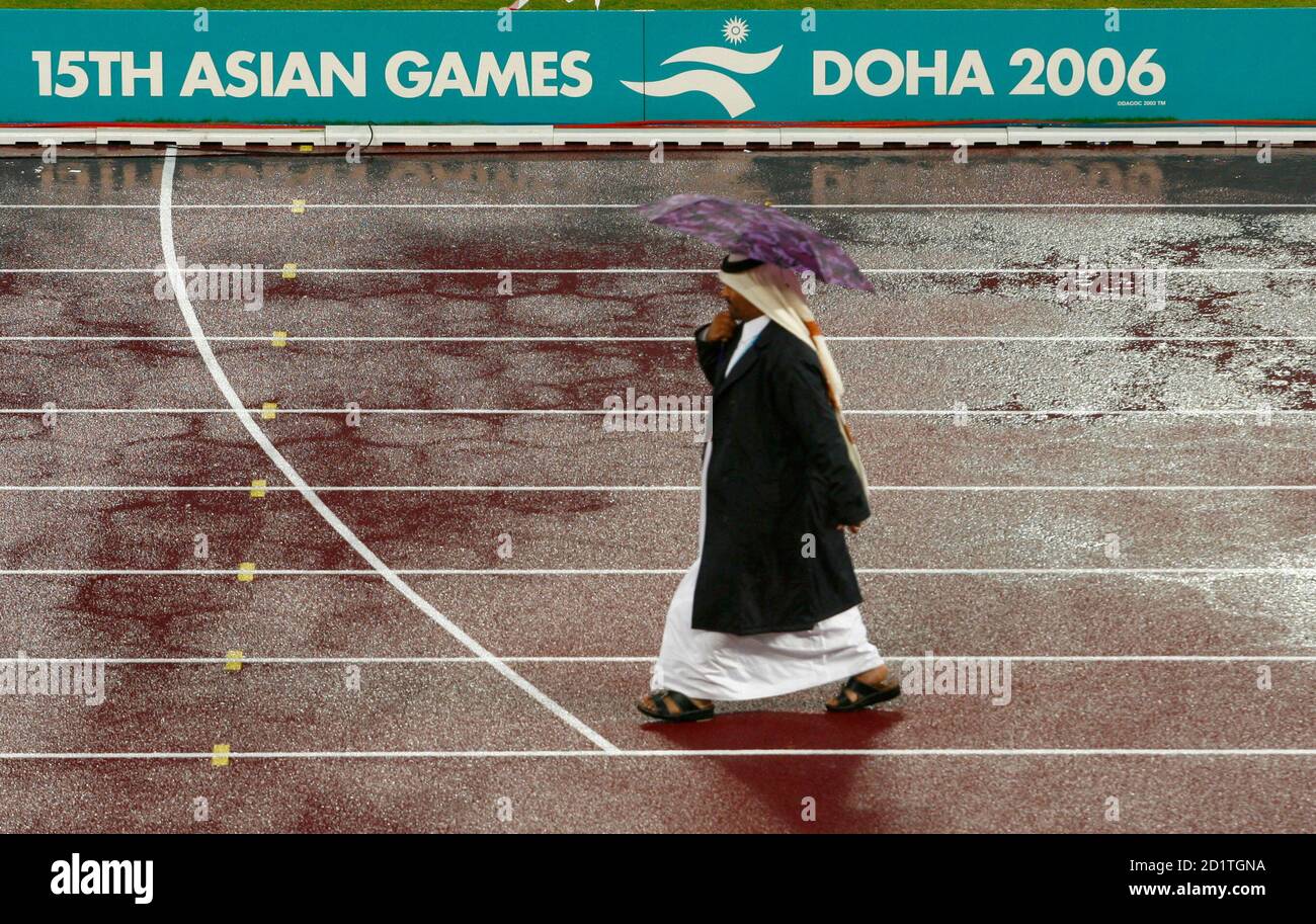 An official walks in the rain at Khalifa Stadium on the seventh day of  official competition at the 15th Asian Games in Doha December 7, 2006.  REUTERS/Jerry Lampen (QATAR Stock Photo - Alamy
