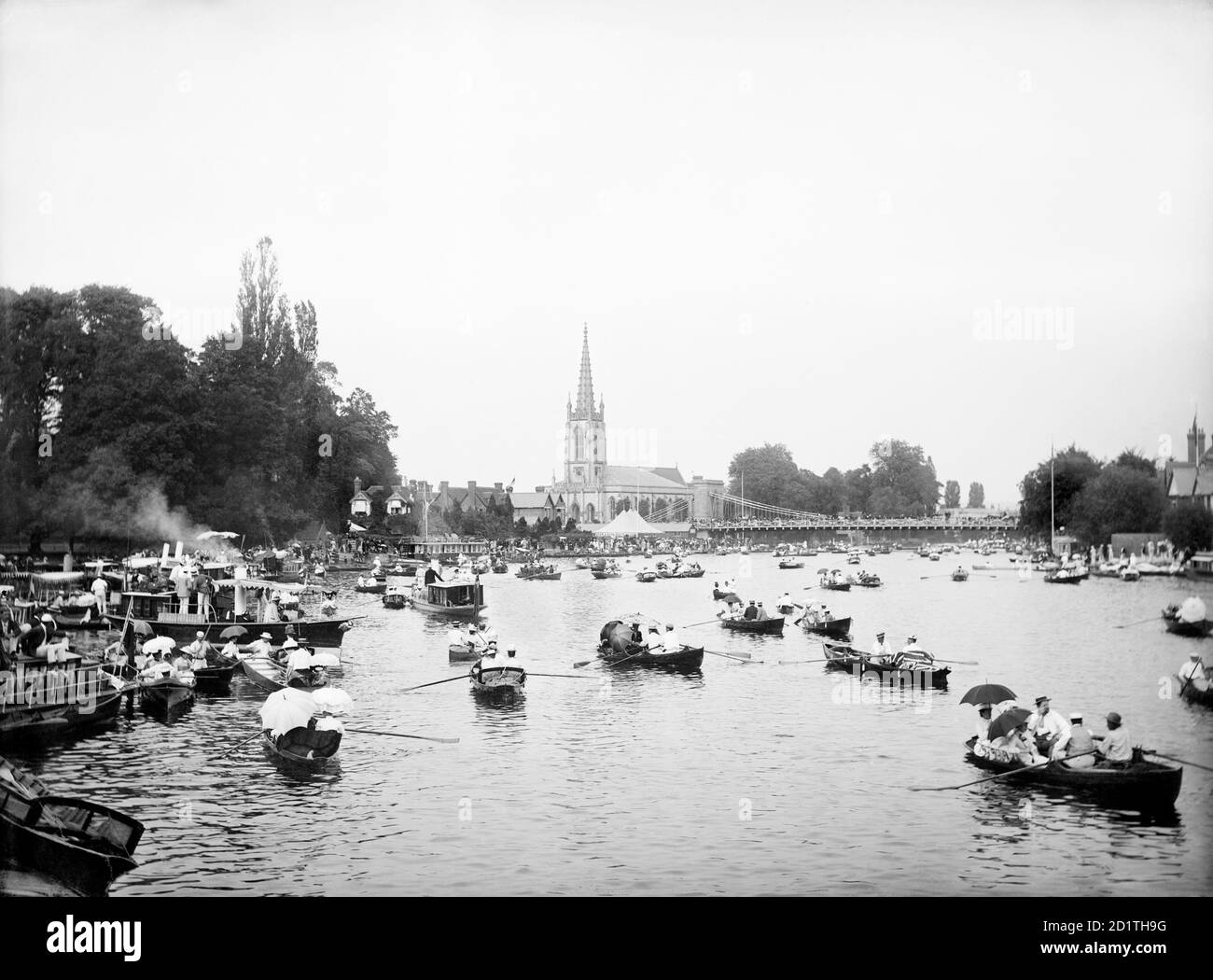 MARLOW, Wycombe, Buckinghamshire. A view of the river filled with small row boats and houseboats during the regatta held annually between at least 1855 and 2001 on the River Thames (it has since transferred to Dorney Lake). With All Saints Church and the suspension bridge beyond. Photographed in 1885 by Henry Taunt. Stock Photo