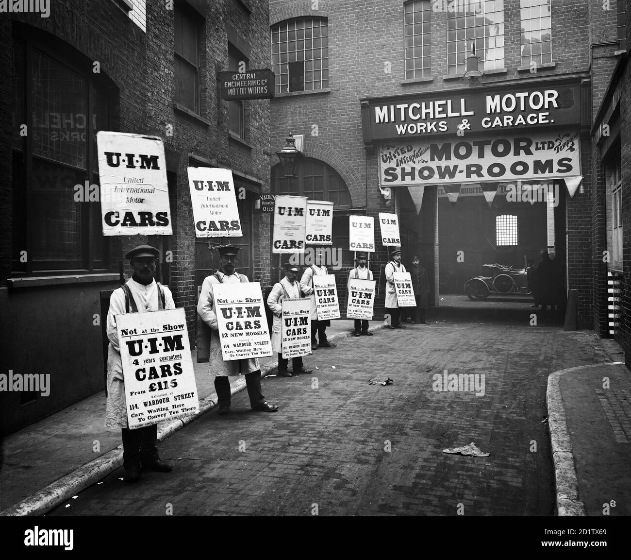 WARDOUR STREET, London. A line of men standing outside Mitchell Motors Company (114 Wardour Street), wearing sandwich boards advertising United International Motors Ltd. At the time the photograph was taken the garage was being used as a temporary motor showroom. Photographed by Bedford Lemere & Co in October-November 1910. Stock Photo