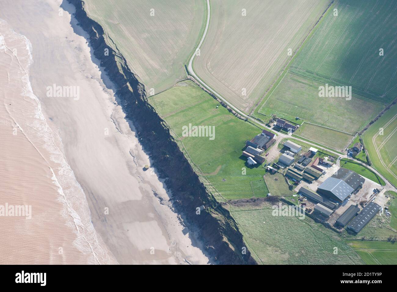 Ridge and furrow earthworks at low farm and evidence of coastal erosion with collapse of pillbox on to beach and second World War engine room (generator house) slipping down the cliff, Aldbrough Sands, East Riding of Yorkshire, 2014, UK. Aerial view. Stock Photo