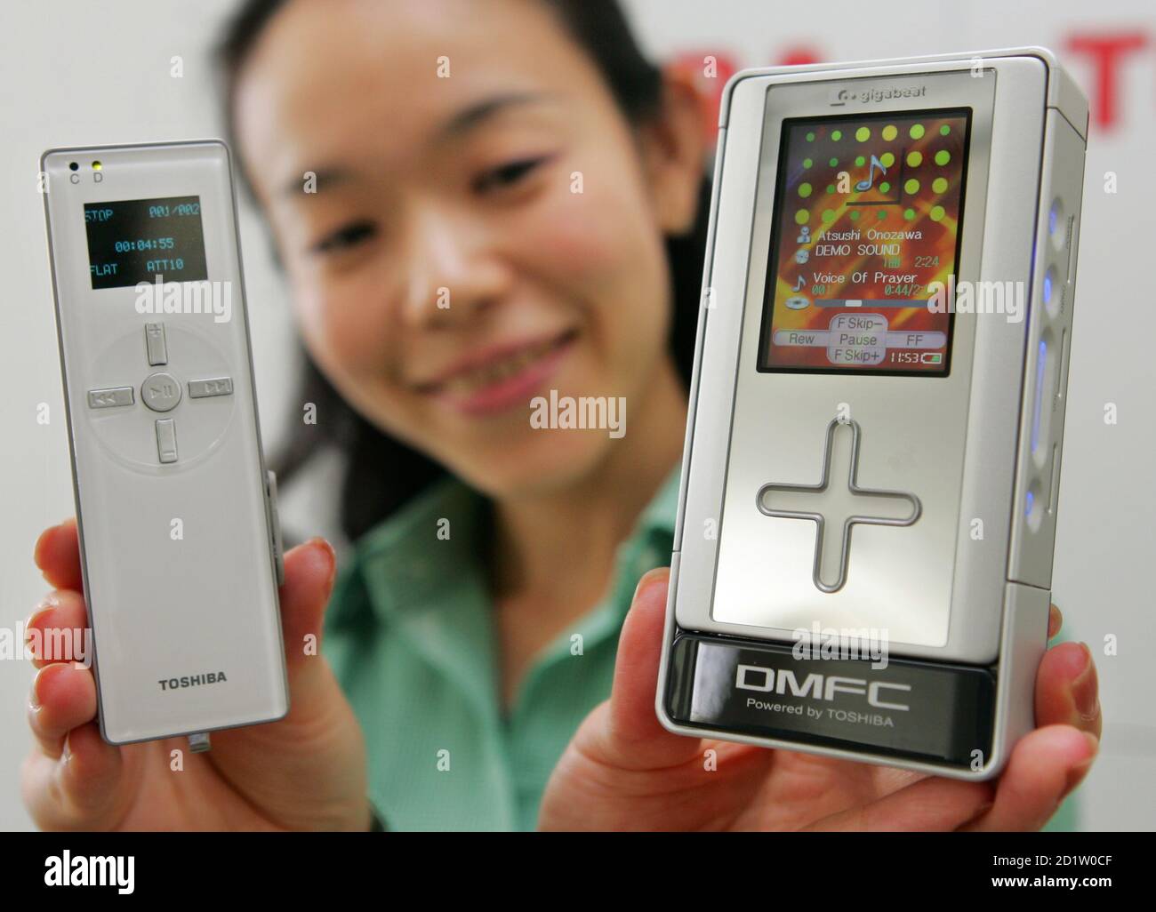 Toshiba employee shows off the company's prototype of direct methanol fuel cell powered audio player in Tokyo.  An employee of Toshiba Corporation shows off the company developed prototype of direct methanol fuel cell (DMFC) powered HDD-based digital audio player (R) and a prototype flash memory-based player at the Toshiba headquarters in Tokyo September 16, 2005. The HDD player can run for approximately 60 hours on a single 10ml charge of pure methanol and the flash-memory player runs for 35 hours on a single 3.5ml charge. The DMFC units can be integrated into devices for digital audio player Stock Photo