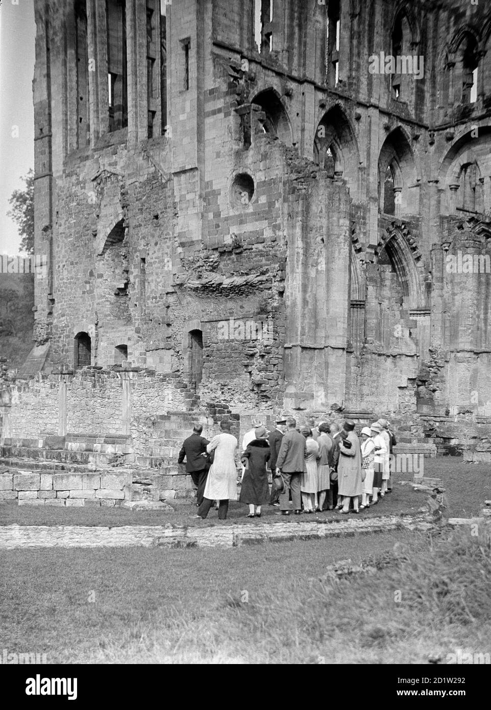 A group of visitors looking at the south side of Rievaulx Abbey, Rievaulx, North Yorkshire, UK. Stock Photo