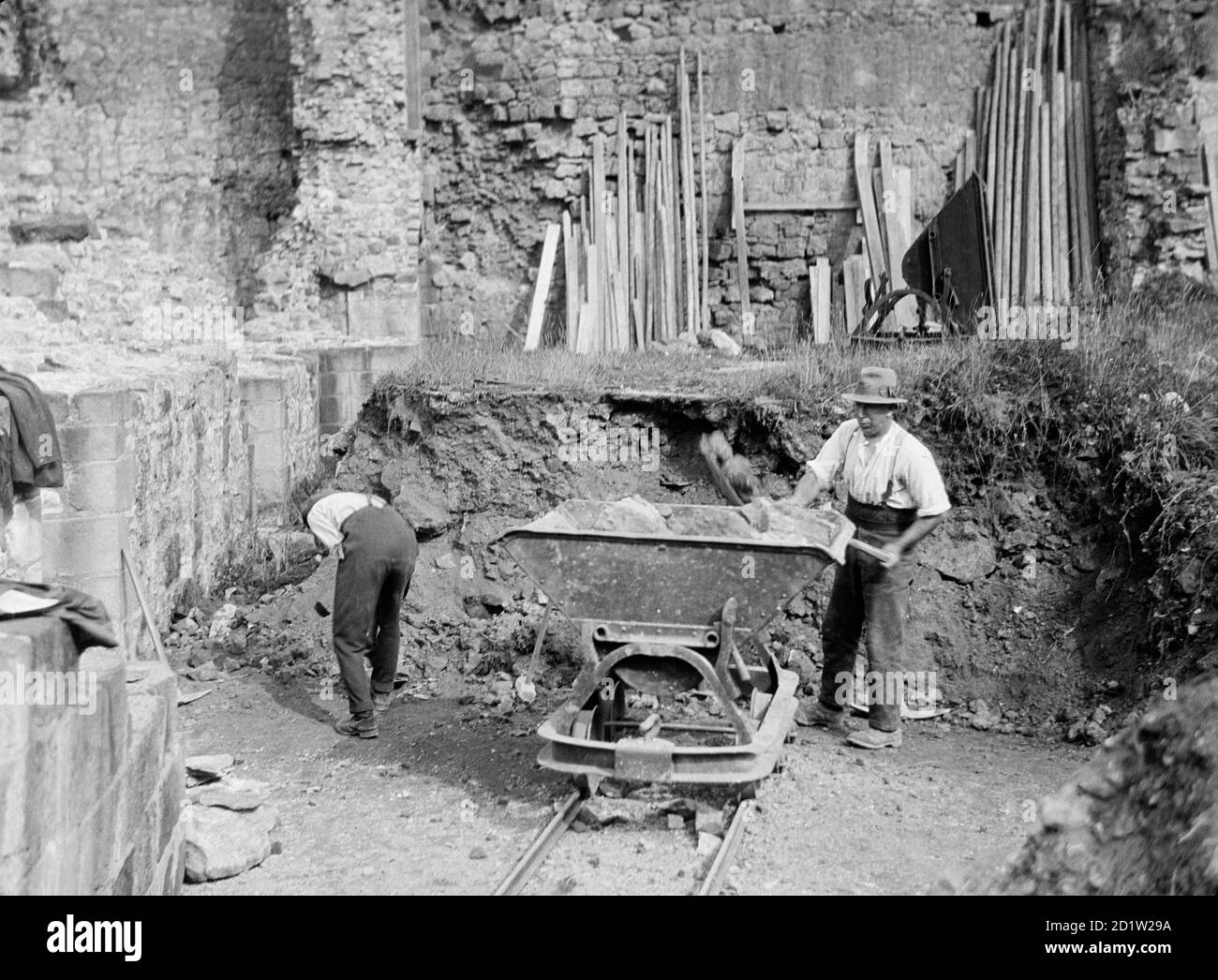 High angle view of two workmen loading a wagon with rubble as part of restoration works to Rievaulx Abbey, Rievaulx, North Yorkshire, UK. Stock Photo