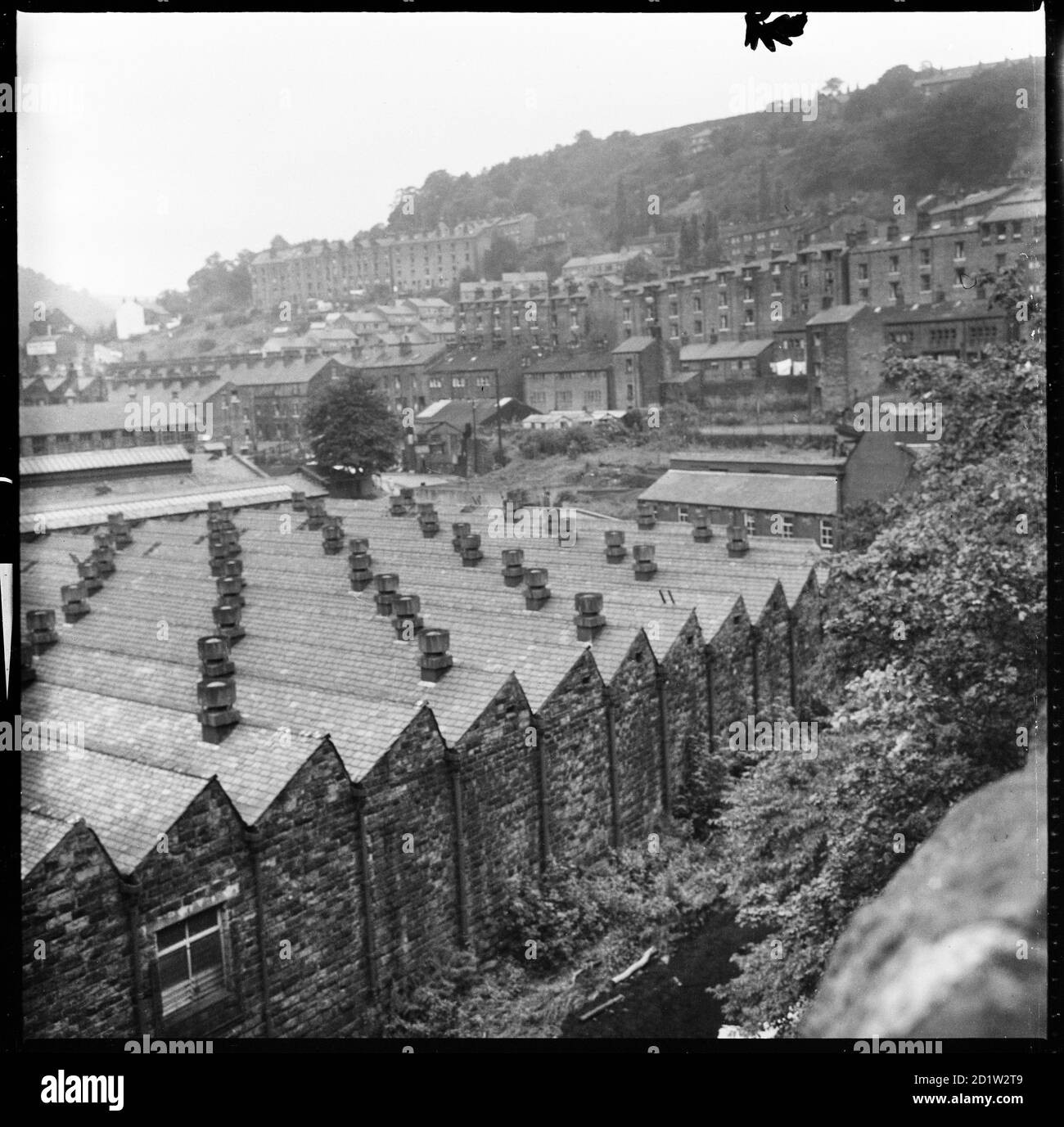 A view looking north across Hebden Bridge with the north lit roofs of Hebden Works in the foreground and the terraces on Lee Mill Road in the distance, West Yorkshire, UK. Stock Photo