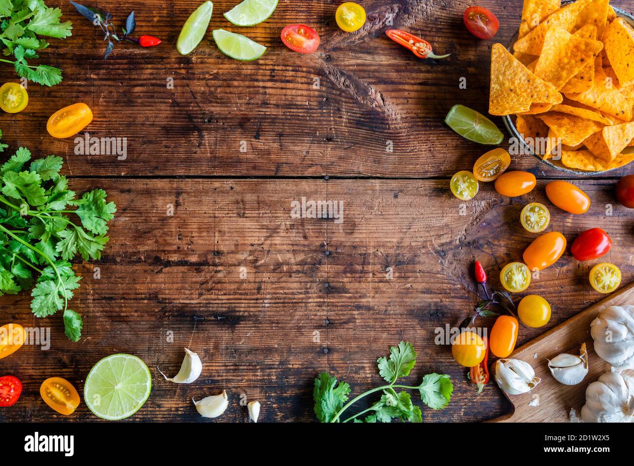Lime, cilantro, chili, nachos background with copy space. Ingredients for Pico de gallo Salsa sauce or other mexican or latin american food. On a rust Stock Photo