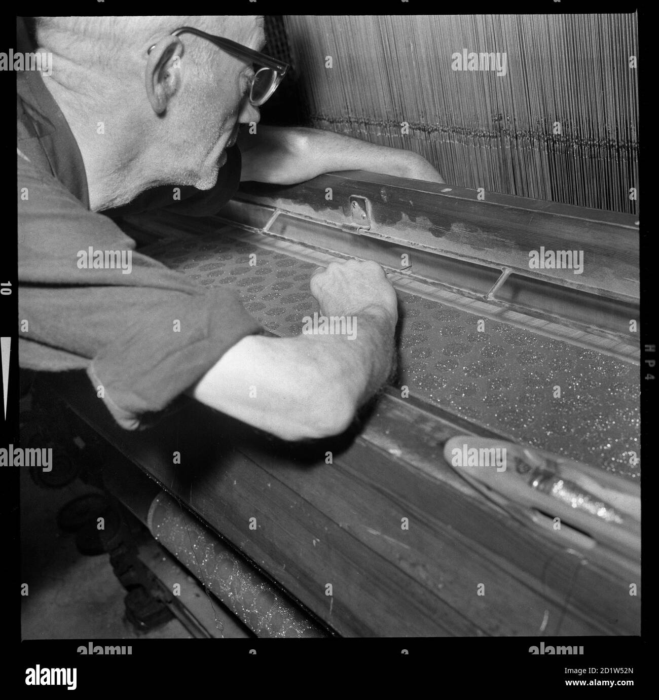 A man adjusting the warp ends in the reed of a Jacquard loom. Stock Photo