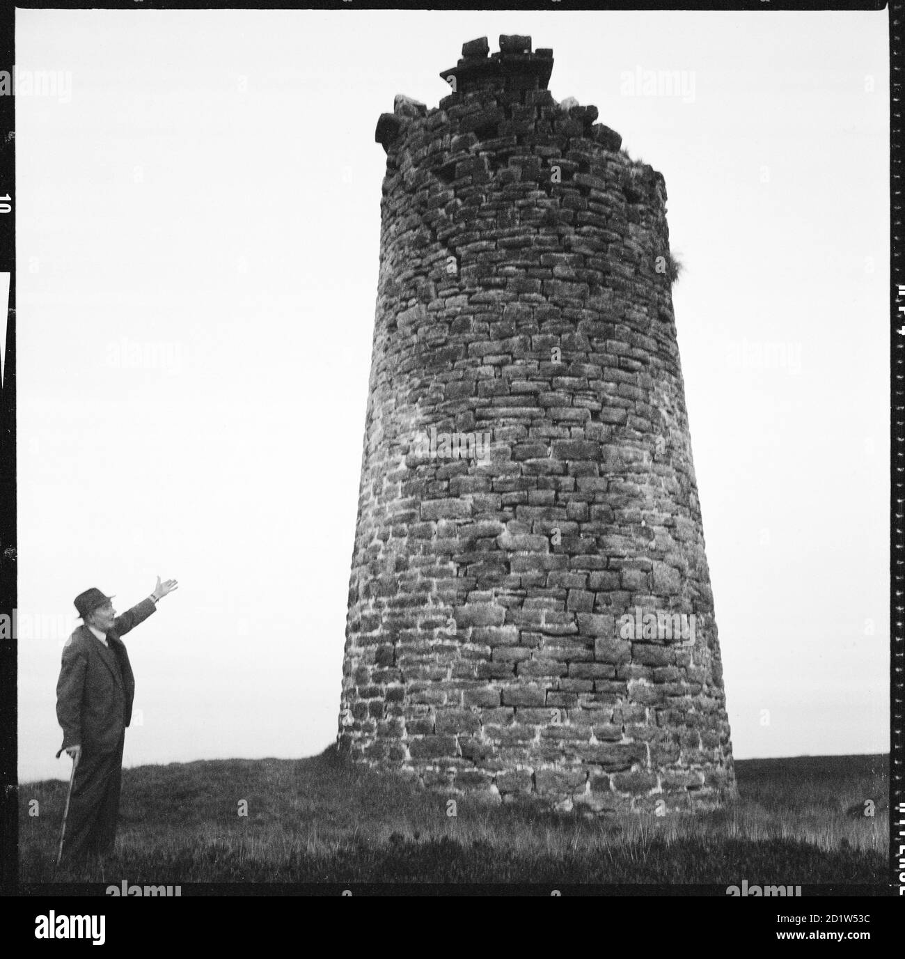 A man posed beside the derelict Cononley Lead Works smelt mill chimney on the summit of Gib Hill, Cononley Lead Mine, Smelt Mill Chimney, Cononley, Craven, North Yorkshire, UK. Stock Photo