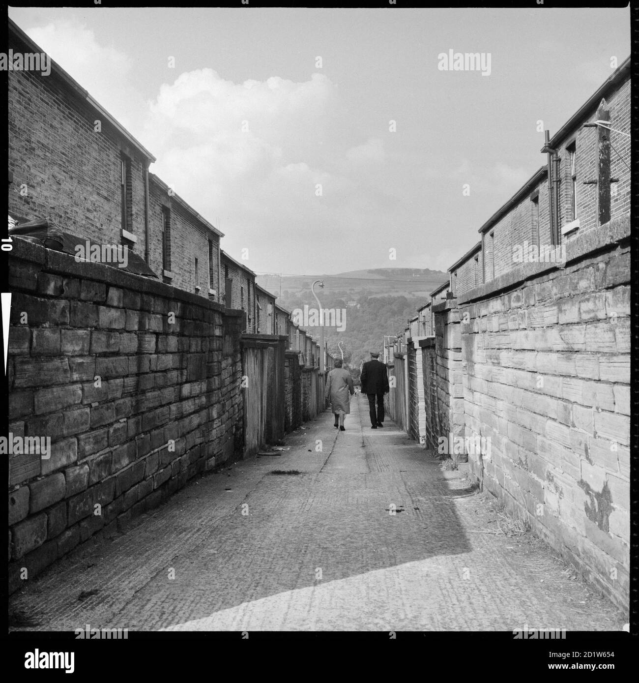 A couple walking along a ginnel (alley) connecting Caroline Street and Albert Terrace with Baildon Moor, Saltaire, Shipley, Bradford, West Yorkshire, UK. Stock Photo