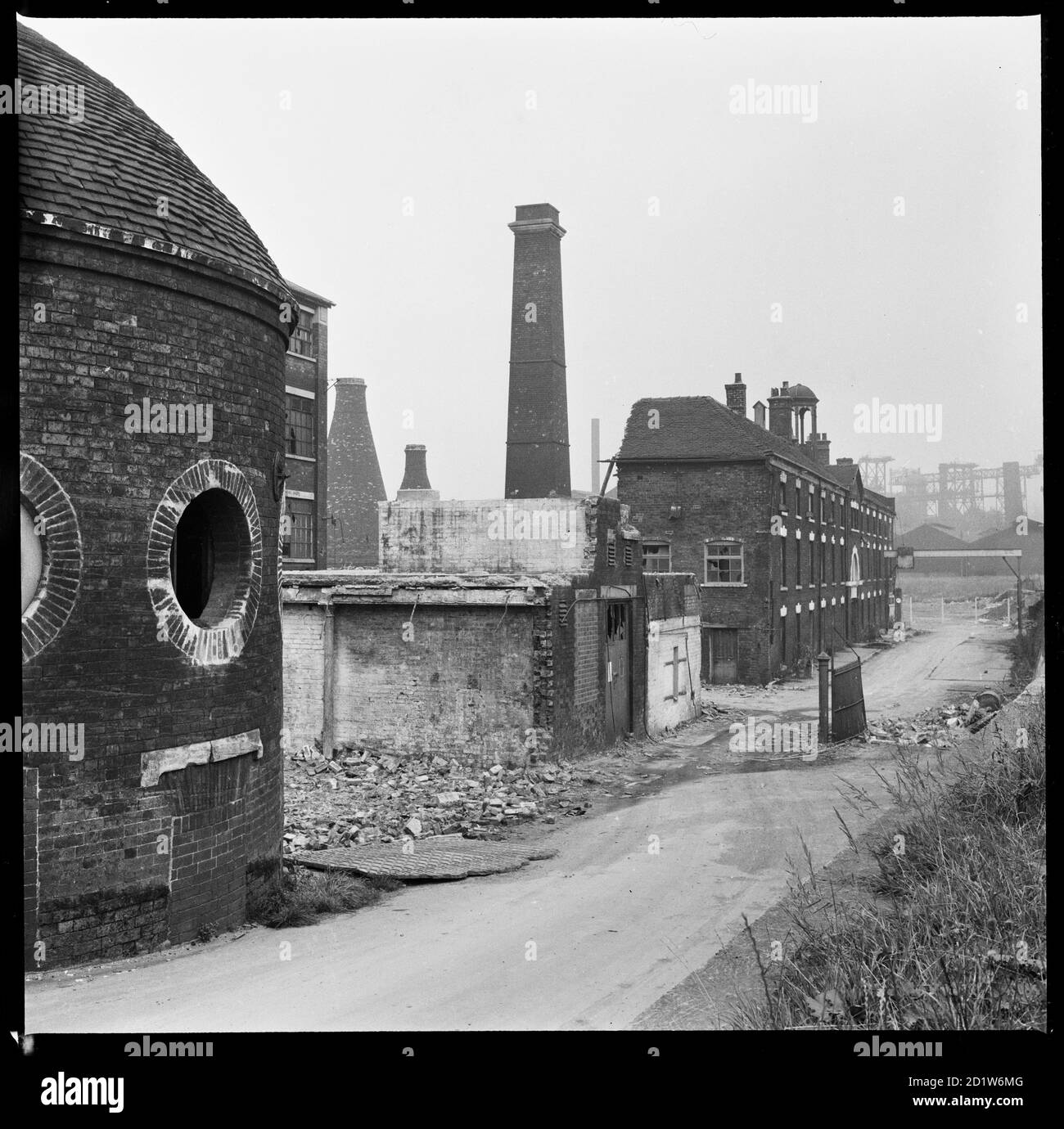 Josiah Wedgwood's Etruria Pottery Works during demolition, viewed from towpath of the Trent and Mersey Canal with the Round House in the foreground, Etruria Road, Etruria, Stoke-on-Trent, Staffordshire, UK.   Josiah Wedgwood opened his Etruria Works beside the Trent and Mersey Canal in 1769. A new factory was constructed at Barlaston in 1938 and production was gradually shifted away from Etruria. The Round House (built circa 1769), said to have been used for grinding raw materials, as a counting house, and as a stable, is now the only surviving structure. Stock Photo