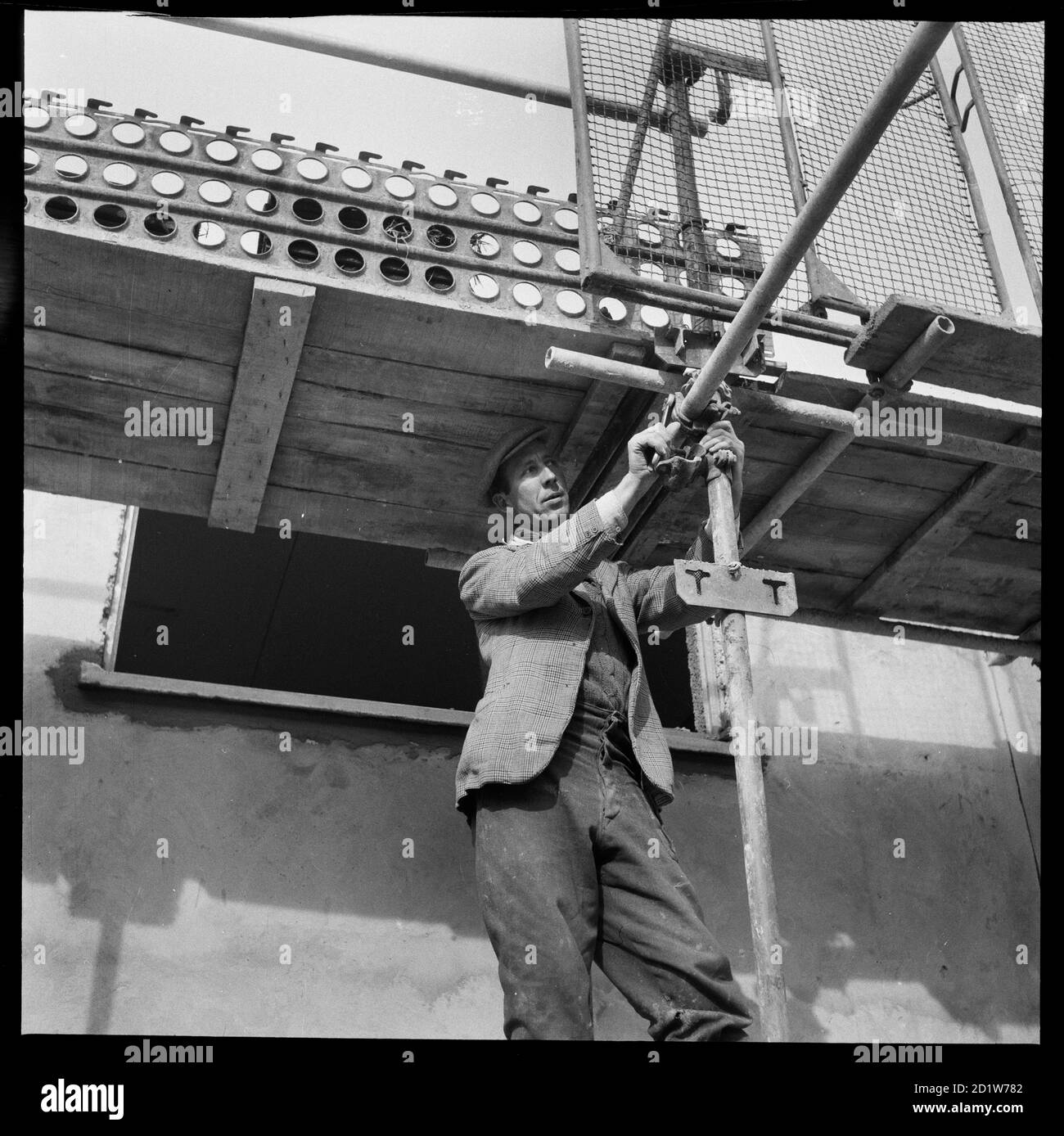 A man assembling scaffolding during construction of the Penhill Estate, Penhill, Swindon, Wiltshire, UK. Stock Photo