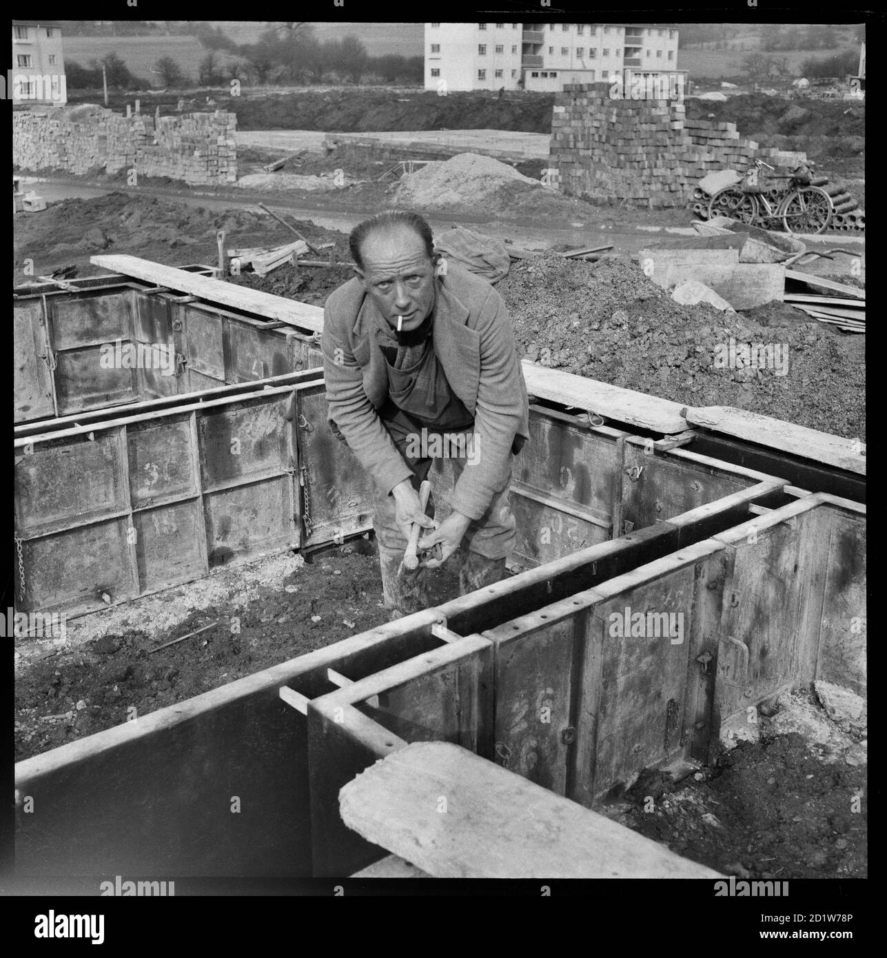 A man working in the concrete footings of houses on the Penhill Estate, Penhill, Swindon, Wiltshire, UK. Stock Photo