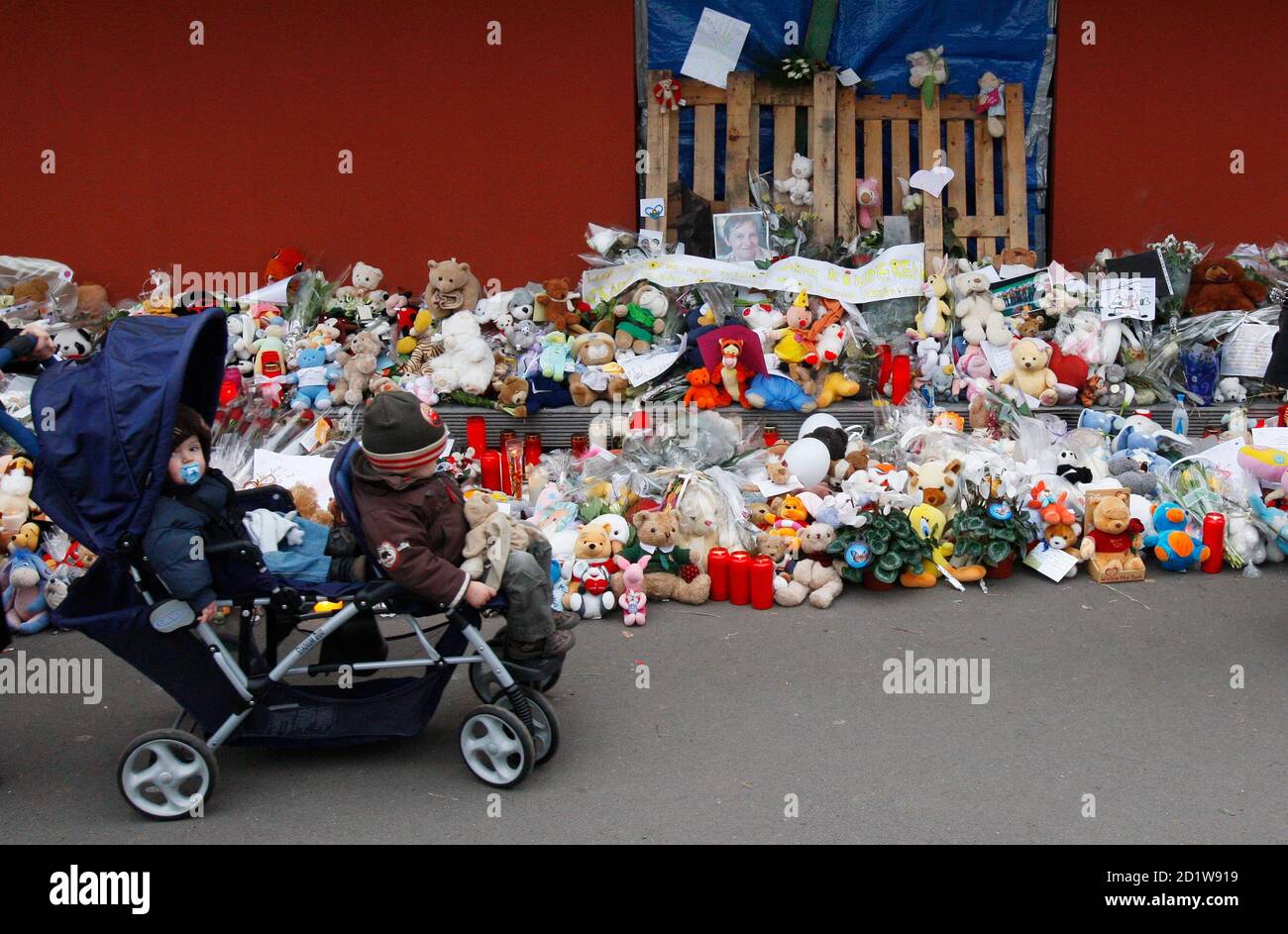 Children pass by flowers placed at the entrance of a creche in Dendermonde January 26, 2009. The man charged with murdering two infants and a woman in a frenzied knife attack at a Belgian child care centre is suspected of killing a 73-year-old woman a week before, prosecutors said on Monday.   REUTERS/Francois Lenoir   (BELGIUM) Stock Photo
