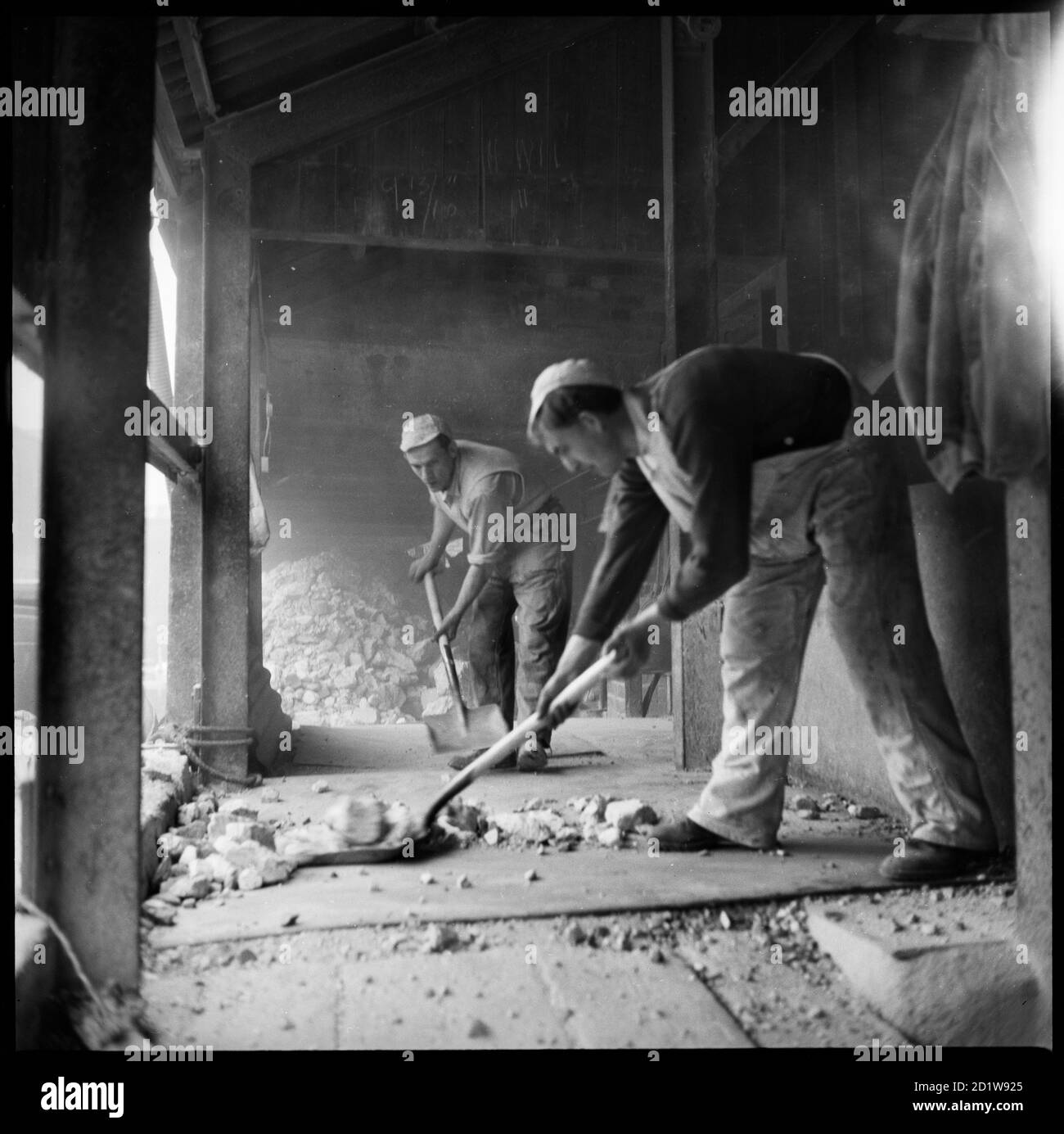 Men shovelling flint at W J Dolby's flint calcinating kiln. Stock Photo