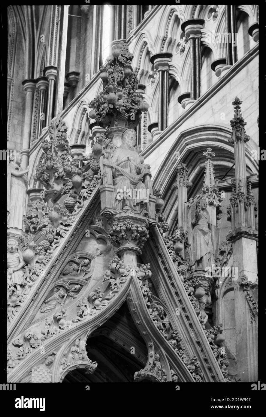 Detail of the top of the ogee arch on the choir-facing side of the Percy Tomb, showing Christ receiveing the soul of a person, with small angelic figures either side of Him, and larger figures stood on the sides of the arch, holding instruments. Stock Photo