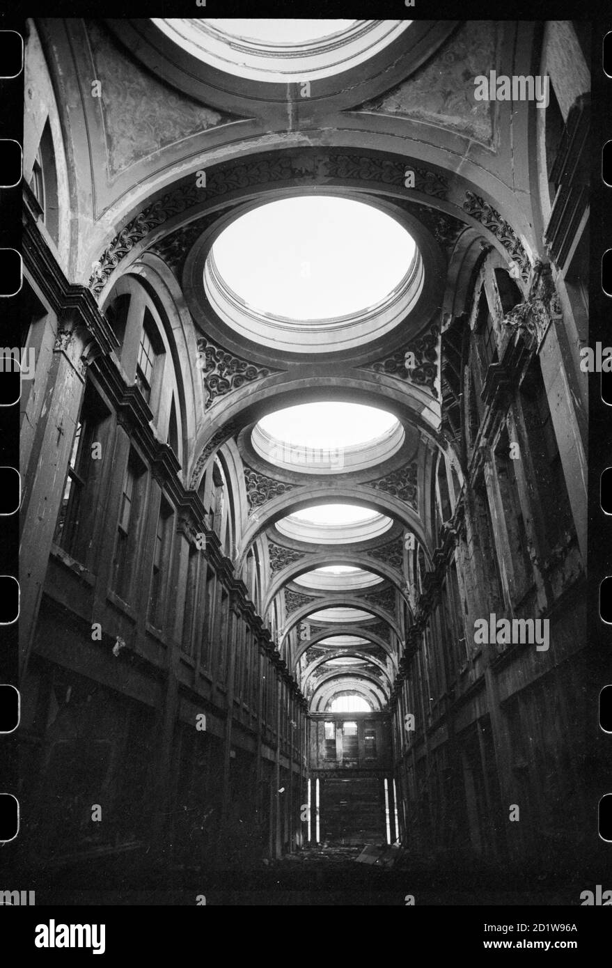 Interior view of the Royal Arcade, built for Richard Grainger and demolished c1963-1964, showing some of the demolition in the central hall, with round roof-lights overhead, and arcades of segmental arches on either side and rubble on the ground, circa 1963 - circa 1964. Stock Photo
