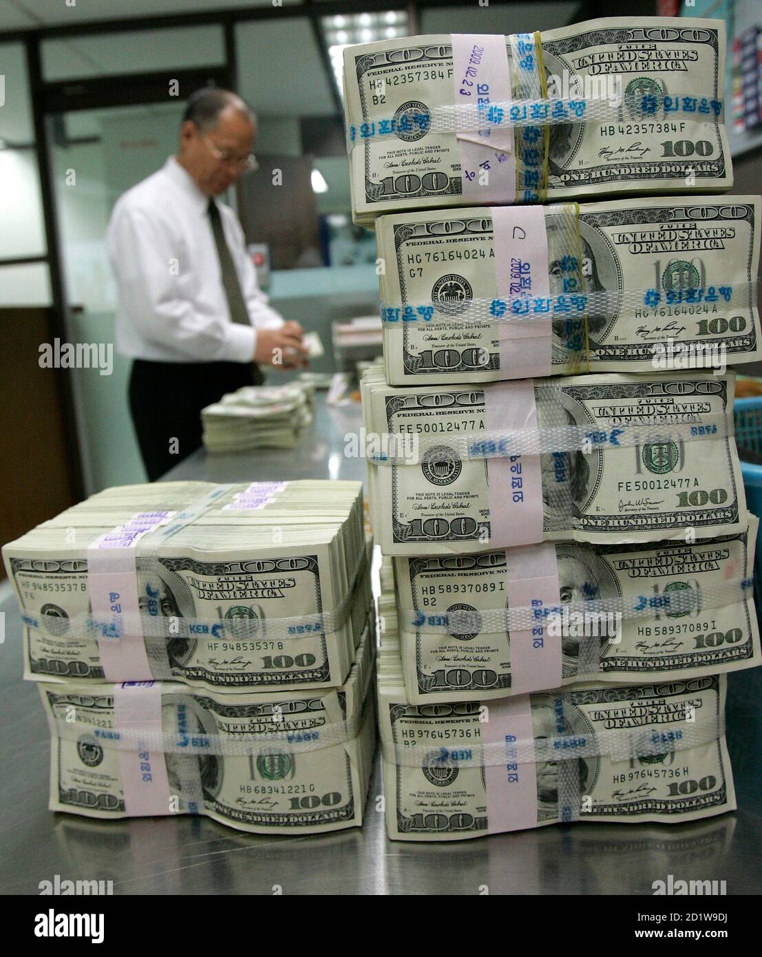 An employee of the Korea Exchange Bank works next to stacks ...