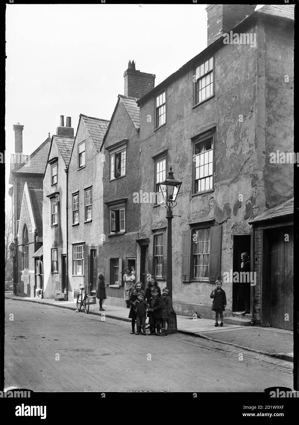 A view of 17th and 18th century houses on the north side of Beef Lane, Oxford, showing the fronts of numbers 4-8 from the south-west, with children in the foreground standing beside a lamp post. Stock Photo