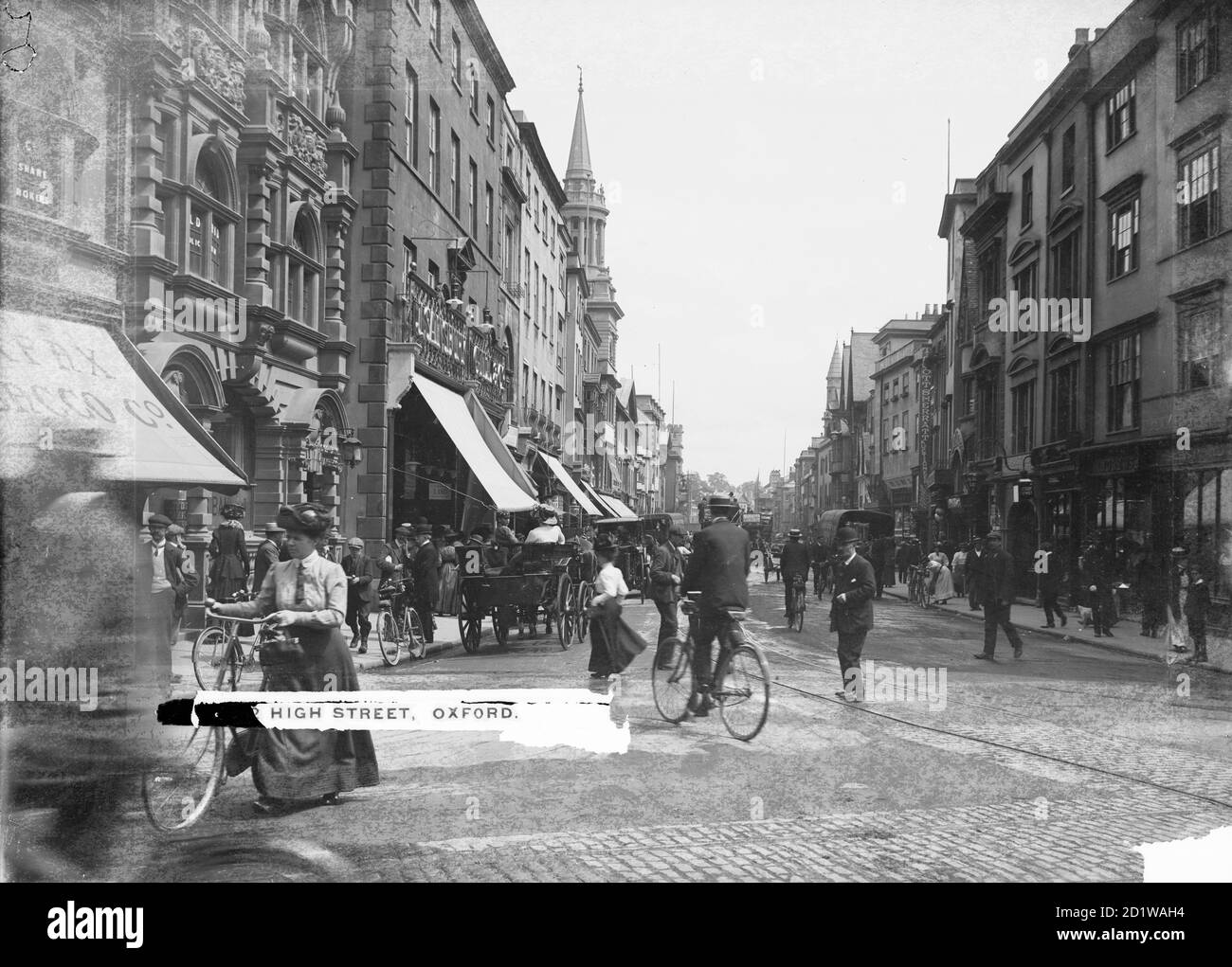 High Street, Oxford, Oxfordshire. Exterior view looking down the busy street from Carfax with horse drawn carts, trams and bicycles in the road. Stock Photo