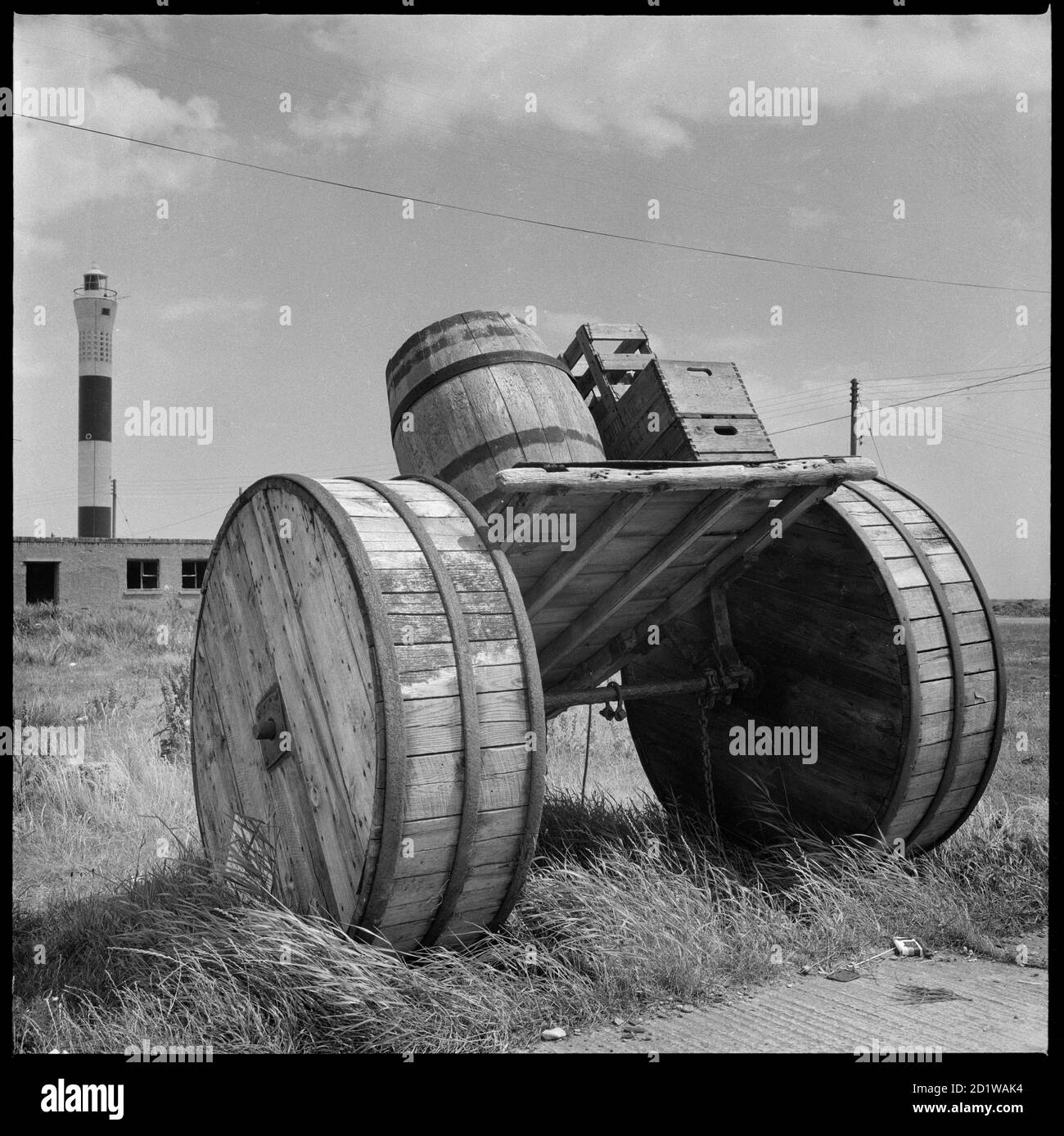 Dungeness, Lydd, Shepway, Kent. A horse-drawn cart loaded with beer crates and a barrel on display in the car park beside Dungeness Old Lighthouse, with the new lighthouse visible in the background. Stock Photo