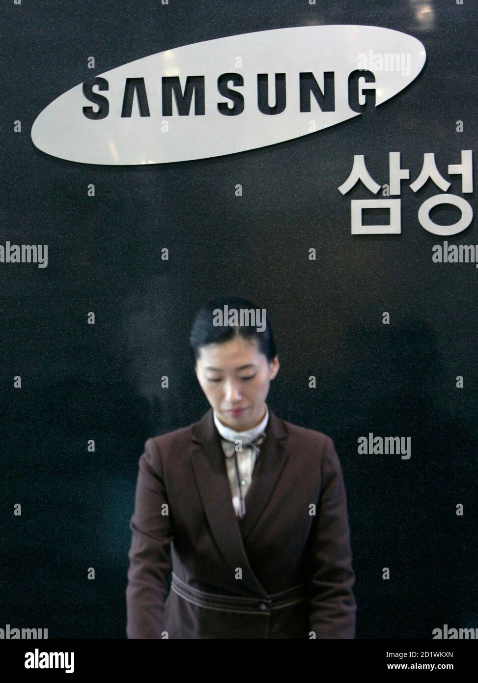 An employee of Samsung Securities stands in front of its logo at the unit's headquarters in Seoul November 30, 2007. South Korean prosecutors probing corruption at the Samsung Group raided its brokerage unit Samsung Securities on Friday and did not rule out further search and seizures at Samsung offices, an official said.  REUTERS/Jo Yong-Hak (SOUTH KOREA) Stock Photo