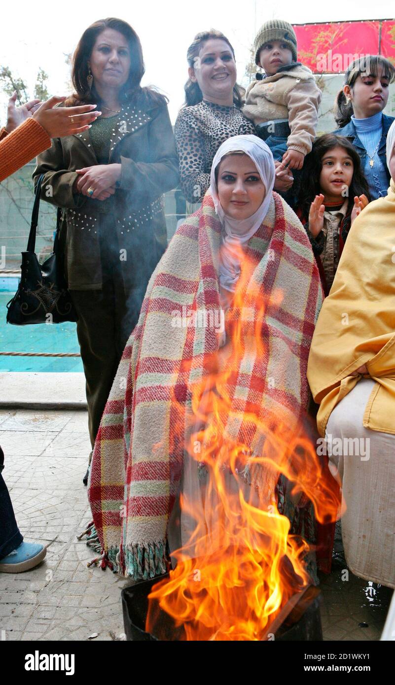 Iraqi Mandean bride Mary Ayed sits next to a fire after being baptised at her wedding ceremony in the Damascus suburb of Jaraman December 2, 2007. Mandean brides must have their virginity checked by other women before they can be baptised. Mandean scholars trace the obscure religion's roots to Adam, whom they say lived 980 million year ago - pushing mankind's origins far earlier than those proposed by science. Almost every ceremony in the religion involves water, and baptism is regarded as the means to ask for forgiveness of sin.  REUTERS/Khaled al-Hariri   (SYRIA) Stock Photo