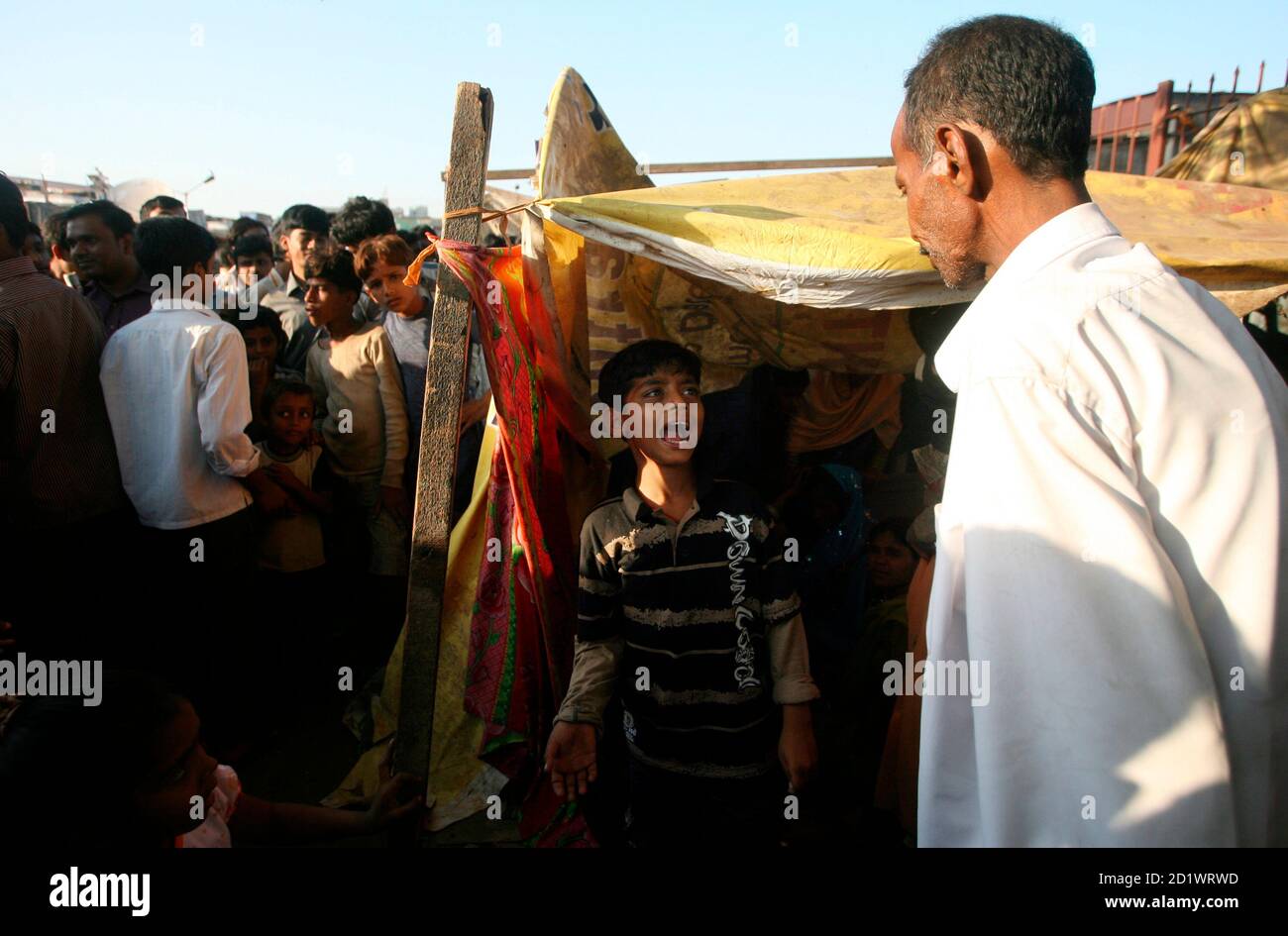 Azharuddin Ismail, who acted in the film "Slumdog Millionaire", reacts speaking to his father (R), after his return from the U.S. in his shack at a slum in Mumbai February 26, 2009. Ismail came back on Thursday after attending the 81st Academy Awards. REUTERS/Arko Datta (INDIA) Stock Photo