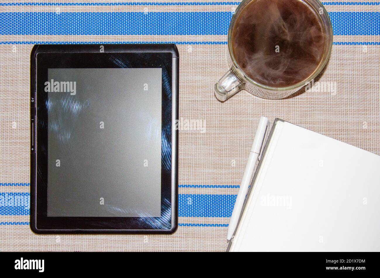 notebook with white pen, tablet PC and coffee on grey wicker background. Stock Photo