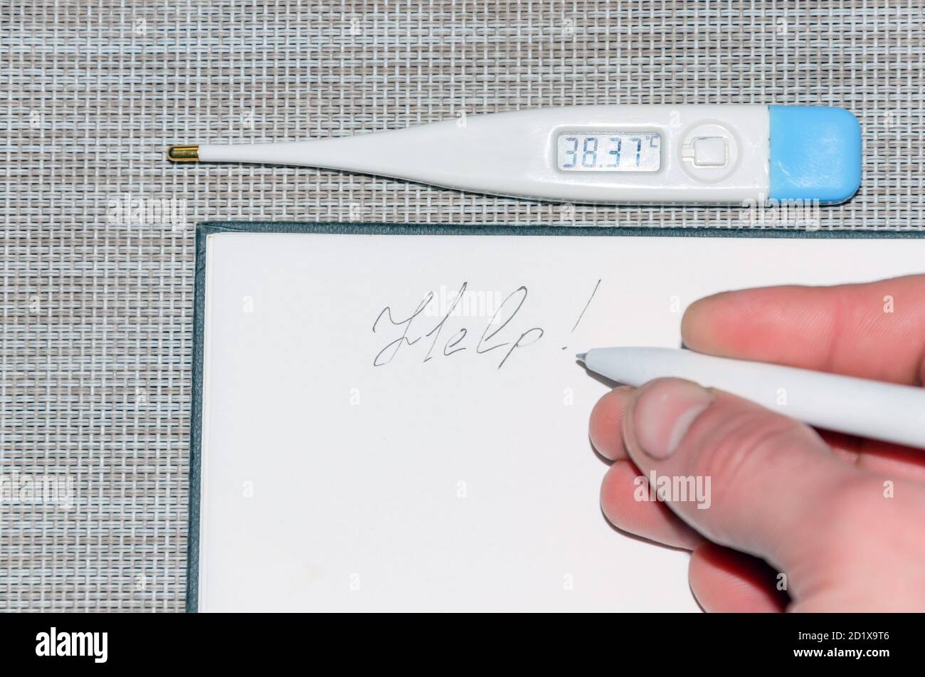 A thermometer with temperature readings and a note in the notebook for help. Stock Photo