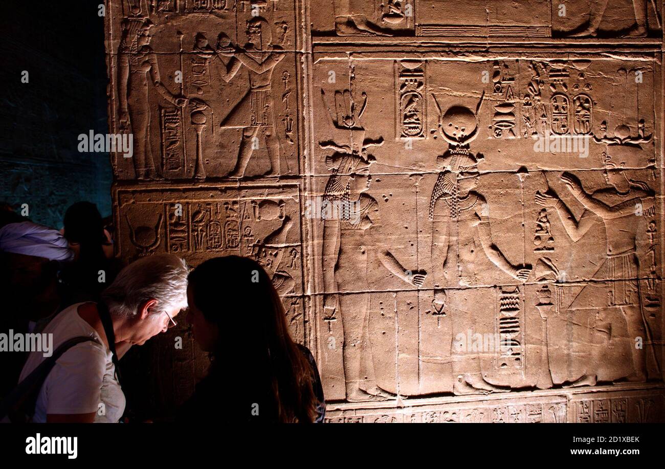 Tourists examine hieroglyphics in the Philae temple complex near the southern Egyptian city of Aswan November 7, 2009. The earliest remains of the temple date from the reign of Nectanebo I in the third century BC and are now one of Egypt's legendary tourist attractions. REUTERS/Goran Tomasevic  (EGYPT SOCIETY) Stock Photo