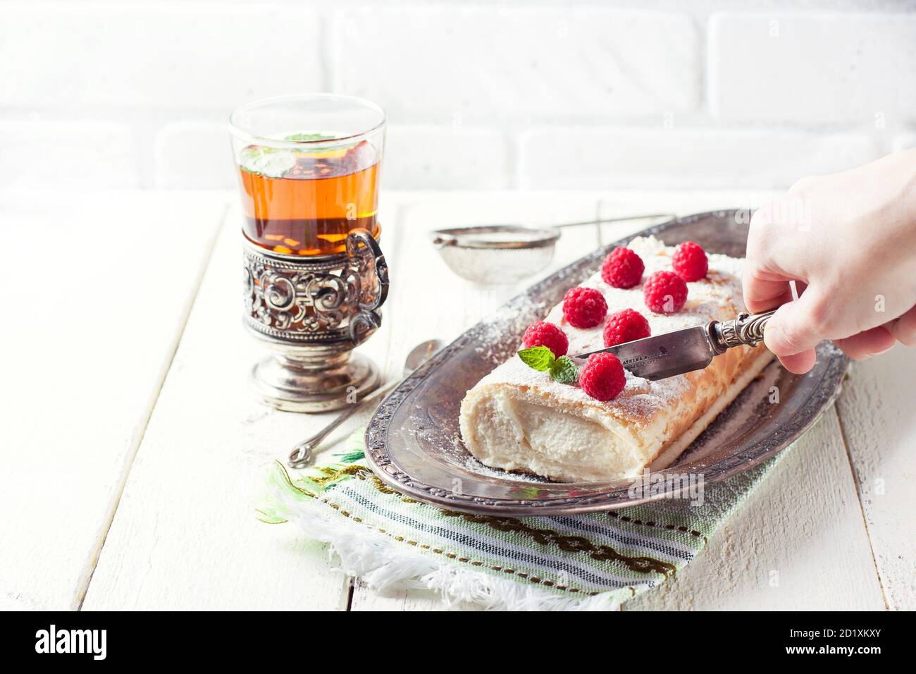 Swiss roll with cream, berries and tea on a light background. Vintage. Stock Photo